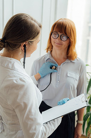 Female cardiologist at Riverside Cardiology Associates using a stethoscope to examine a female patient's heart