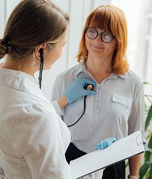 Female cardiologist at Riverside Cardiology Associates using a stethoscope to examine a female patient's heart