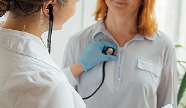 Female cardiologist at Riverside Cardiology Associates using a stethoscope to examine a female patient's heart